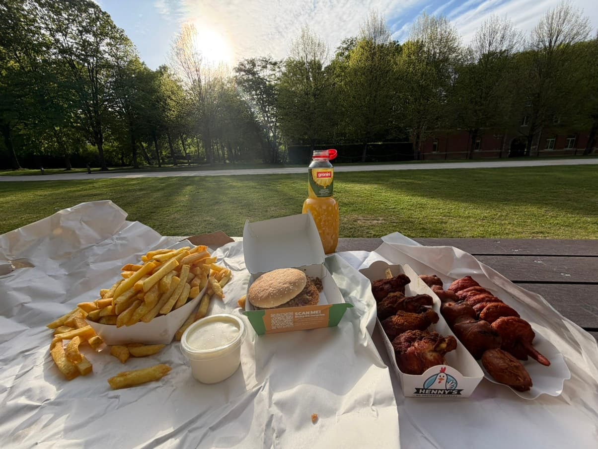 Frietjes en kippenvleugels op een picknicktafel in het park bij zonsondergang